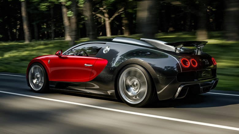 Red-and-black Bugatti Veyron, rear three-quarter view driving on a tree-lined road (motion blur)