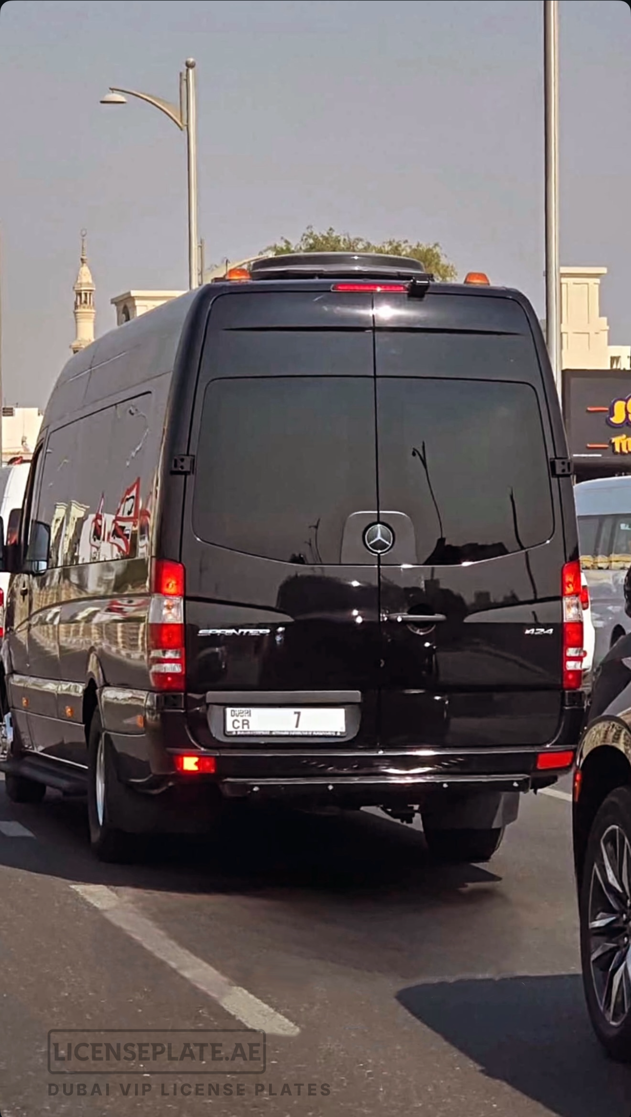 Rear view of a black Mercedes Sprinter van with Dubai license plate CR 7 in city traffic.